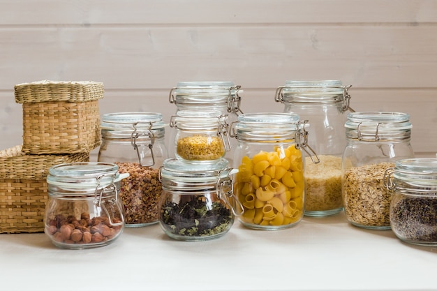 Assortment of uncooked grains cereals and pasta in glass jars on wooden table healthy cooking clean eating zero waste concept 