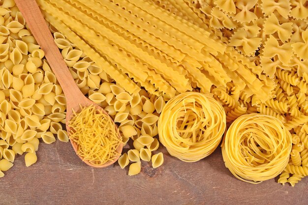 Foto assortimento di pasta italiana cruda su uno sfondo di legno da vicino