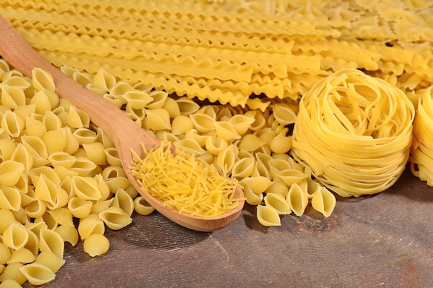 Assortment of uncooked Italian pasta on a wooden background close up