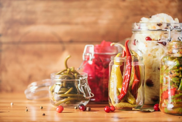 Assortment of various fermented and marinated food over wooden background copy space Fermented vegetables sauerkraut pepper garlic beetroot korean carrot cucumber kimchi in glass jars