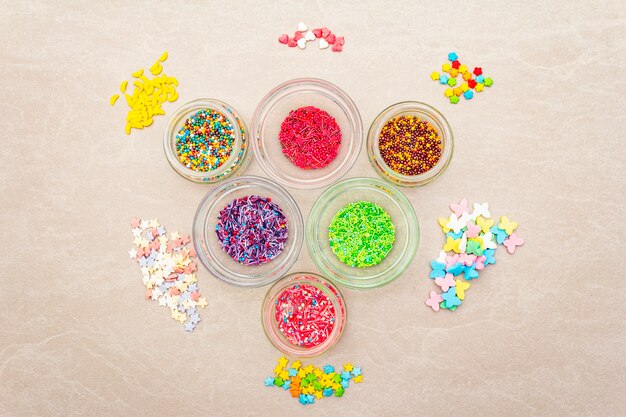 Assortment of various sugar sprinkles, Food surface. In glass bowls on stone surface, .