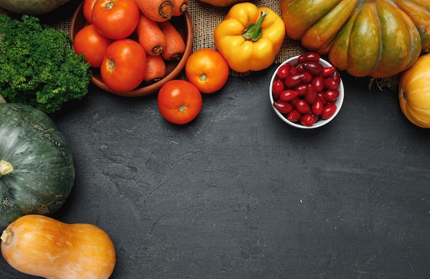 Assortment of vegetables including pumpkin, tomatoes and peppers with greens on black