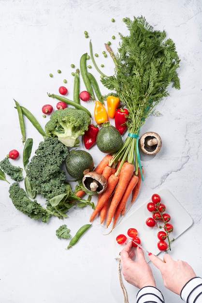 Assortment of vegetables and women's hands cutting tomatoes