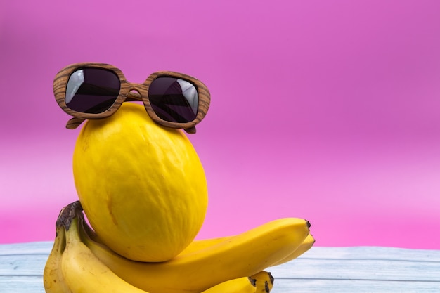 An assortment of yellow fruits and glasses lies on a pink background