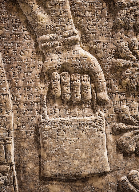 Assyrian wall relief of winged genius detail with a hand