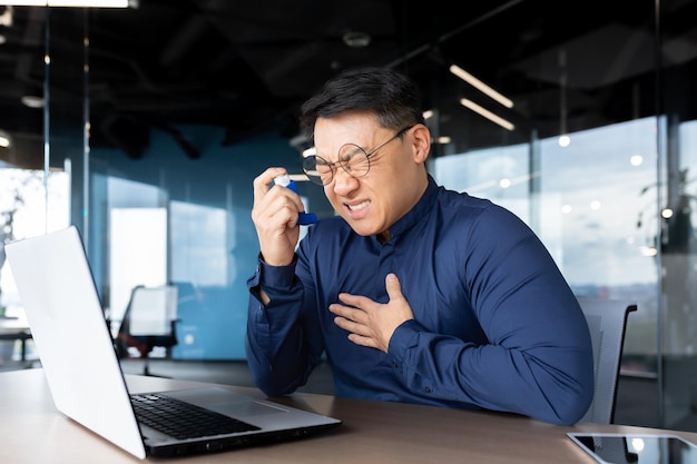 흡입기와 약을 사용하여 사람을 호흡하는 데 어려움을 겪는 아시아 사업가의 천식 발작