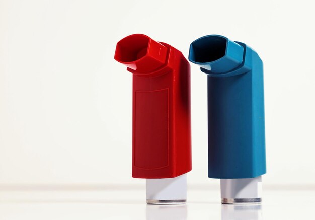 Photo asthma inhalers in red and blue isolated on a light background copy space