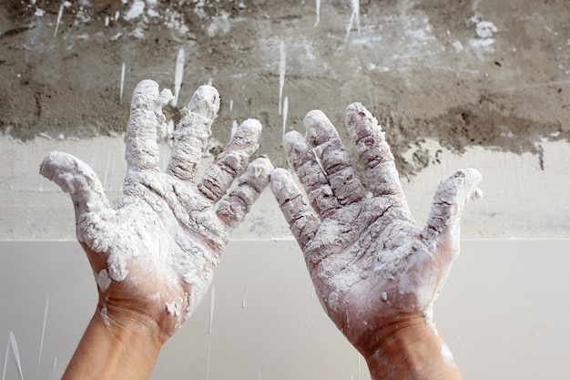 Astist plastering man hands with cracked plaster