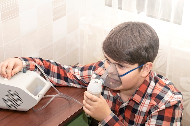 Astma bij kinderen. de jongen inhaleert het medicijn voor de inhalator.