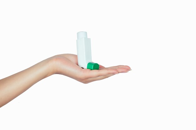 Astma-inhalator in de hand op wit isolaat