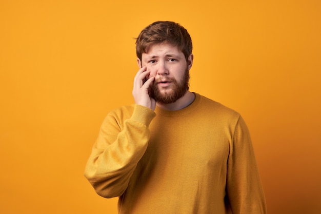 Astonished attractive male has ginger long beard, wonders sudden news, keeps mouth slightly opened, stares at camera, wears casual clothes and spectacles, poses against white wall with blank space