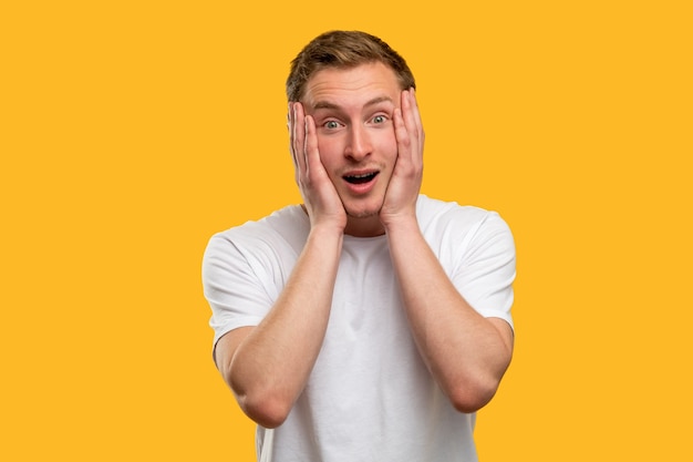 Astonished man portrait. unbelievable news. amazed guy touching head isolated on orange background