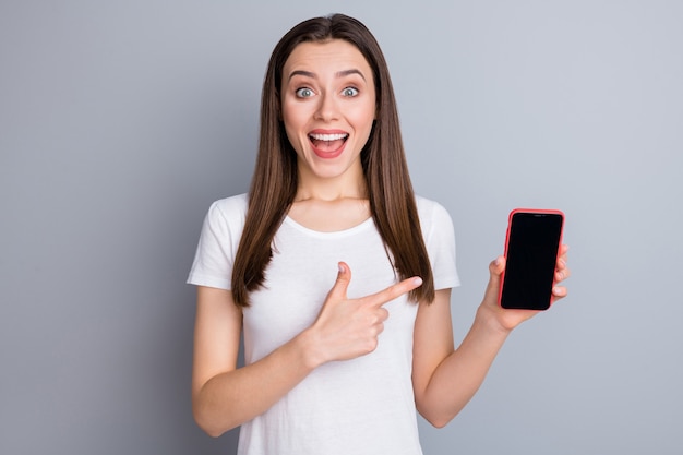 Astonished positive crazy girl promoter hold smartphone point index finger