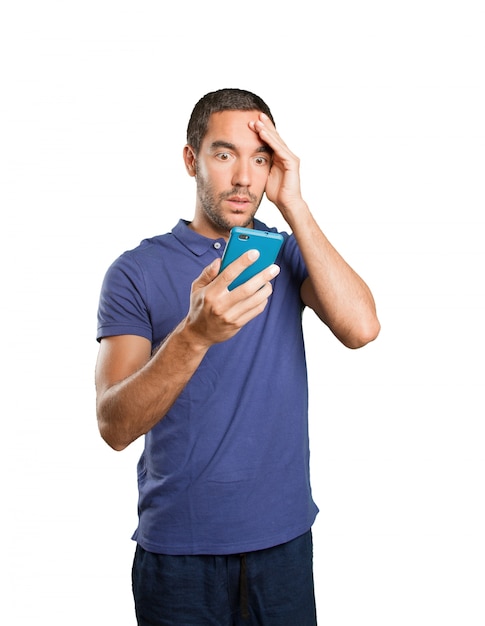 Astonished young man using a mobile phone on white background