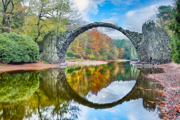 Photo astonishing autumn landscape in azalea and rhododendron park kromlau rakotz bridge rakotzbrucke devil's bridge location gablenz state of saxony germany europe