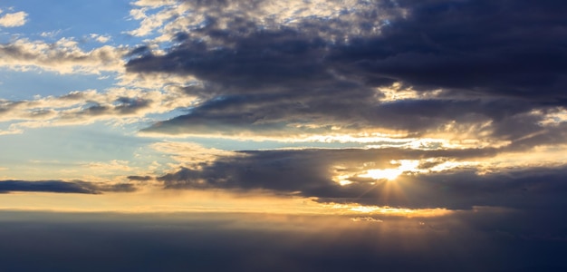 Astonishing view of sunset with dark clouds and golden sunbeams