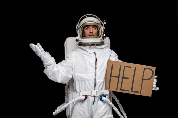 Astronaut day spaceman in galaxy space suit helmet waiting for HELP sign written on cupboard