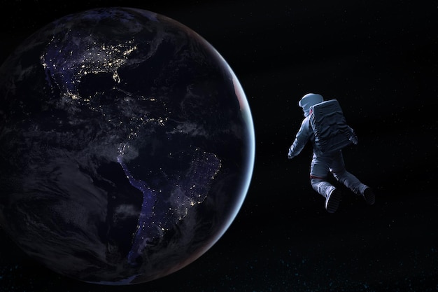 Astronaut in deep space looks on night Earth planet Elements of this image furnished by NASA