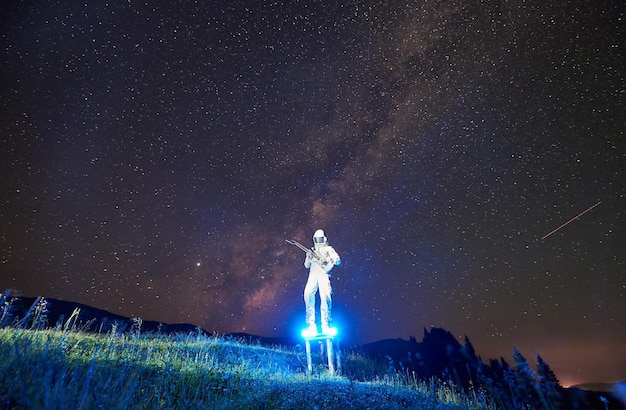 Astronaut die gitaar speelt onder een prachtige nachtelijke hemel