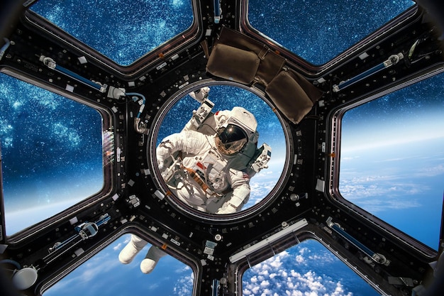 惑星地球を背景に宇宙空間にいる宇宙飛行士。 NASAによって提供されたこの画像の要素。