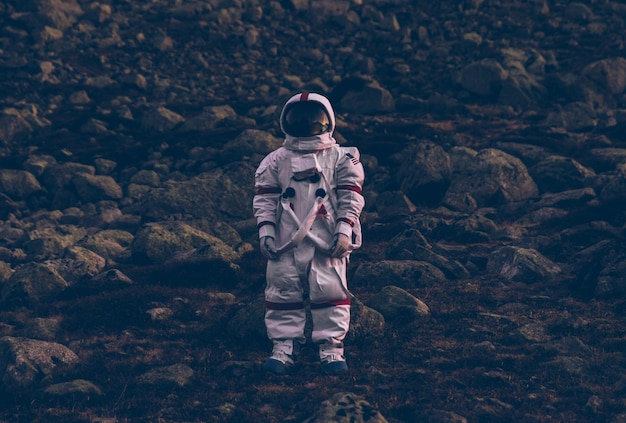 Astronaut staat op het land tegen een berg.