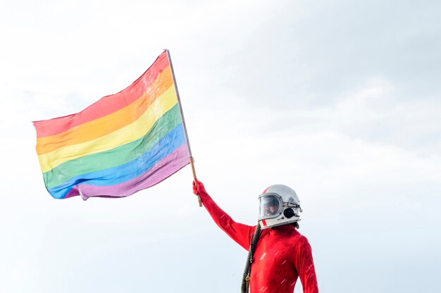 Astronauta con casco che tiene una bandiera del gay pride.concepto lgbt