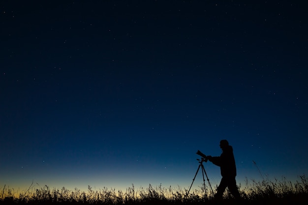 천문학자는 삼각대를 사용하여 디지털 카메라로 별이 빛나는 밤하늘을 촬영합니다.