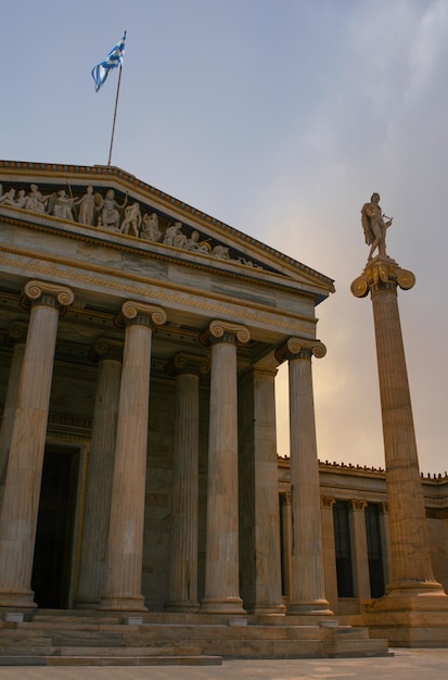 Athene Academie een marmeren zuil met een beeldhouwwerk Apollo tegen een met wolken in Athene, Griekenland