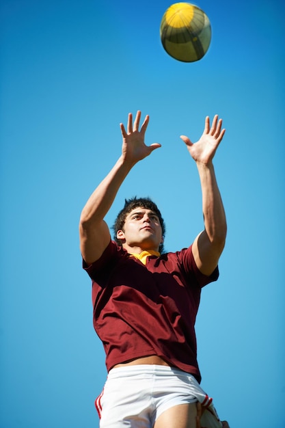 Athlete ball and rugby player catching in training on a blue sky background for sport Professional male person uniform and confident fit exercise or workout for game with a sportsman outdoors