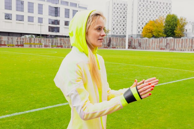 An athlete before training A young woman stretches using an elastic band in an outdoor stadium