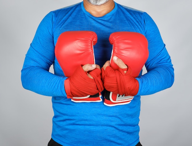 Photo athlete in blue clothes holding a pair of leather boxing gloves