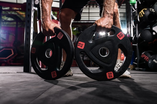 Athlete bodybuilder holding dumbbell discs in hand