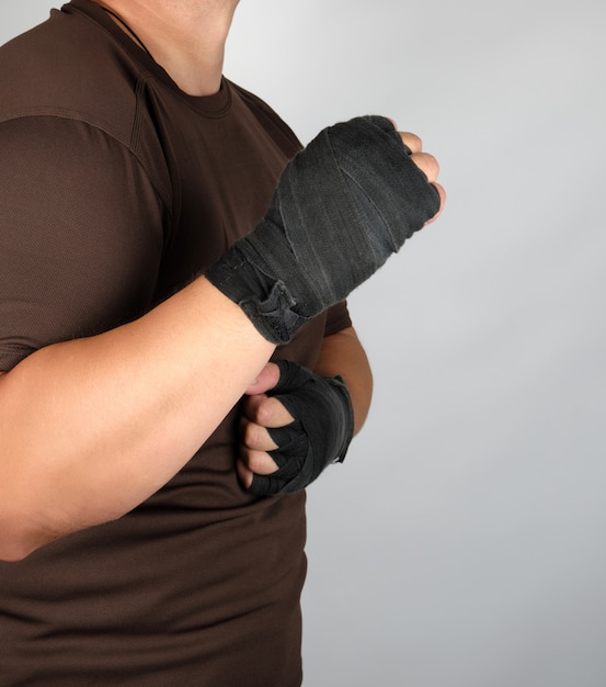 Athlete in brown clothes with bandaged hands black textile sports bandage