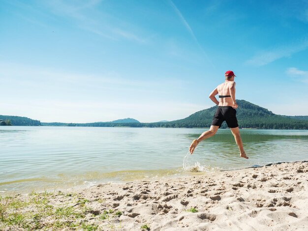 Athlete check heart activities during run in morning bare foots runner run in water just in shorts