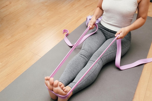 Athlete Exercising with Rubber Tape at Home Woman doing stretching at home with rubber bands