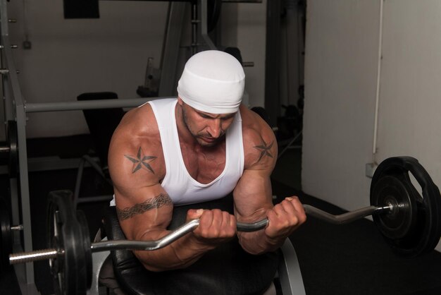 Athlete In The Gym Performing Biceps Curls With A Barbell