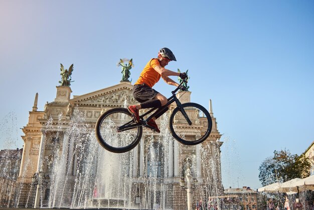 Athlete in helmet performing stunt in front of a fountain