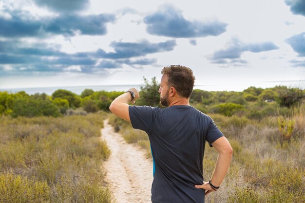 Foto atleta sulla schiena che guarda il suo smartwatch in natura