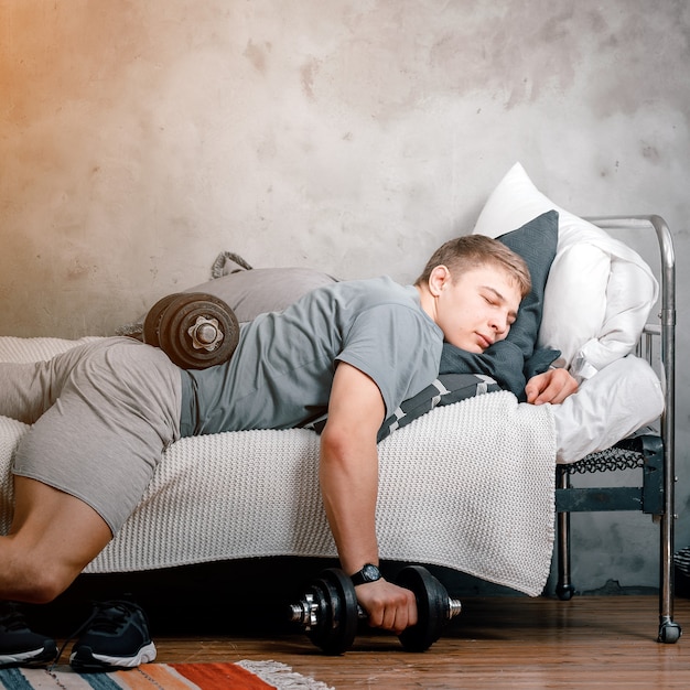 Photo the athlete is lounging, resting  with dumbbells and postponing training at home. the concept of proastination, sports laziness