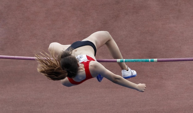 Athlete jumping over the bar in the pole vault sport