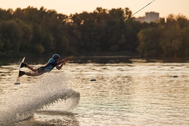 An athlete jumps over the water Wakeboard park at sunset Rider performs a trick on the board