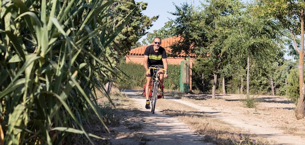 Athlete man driving a bicycle with suitcases