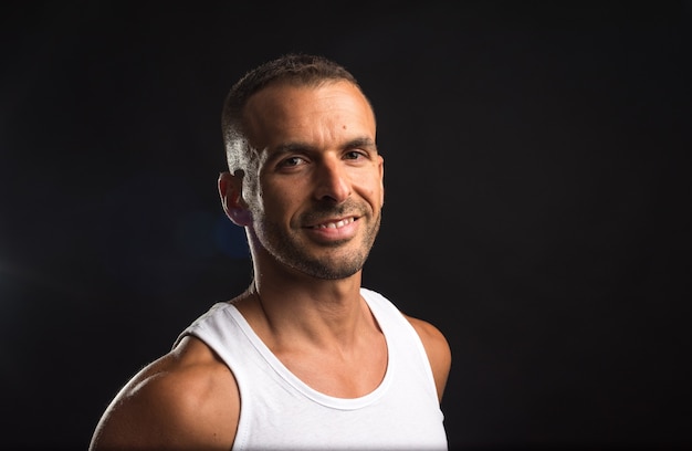 Athlete man in tank top. Close up. Black background.