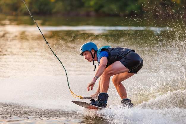 An athlete performs a trick on the water Park at sunset Wakeboard rider