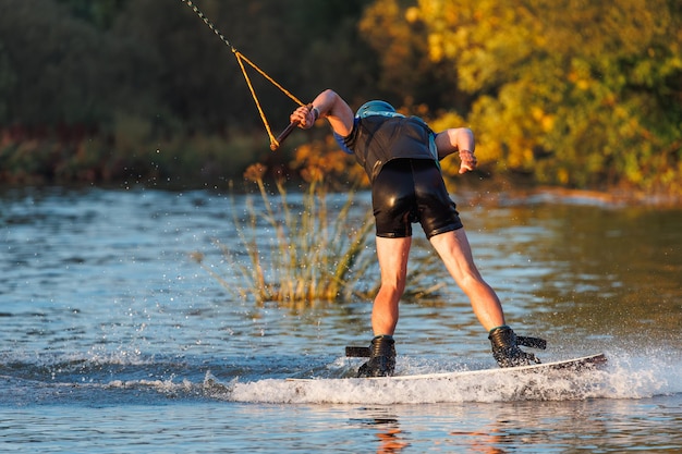 An athlete performs a trick on the water Park at sunset Wakeboard rider