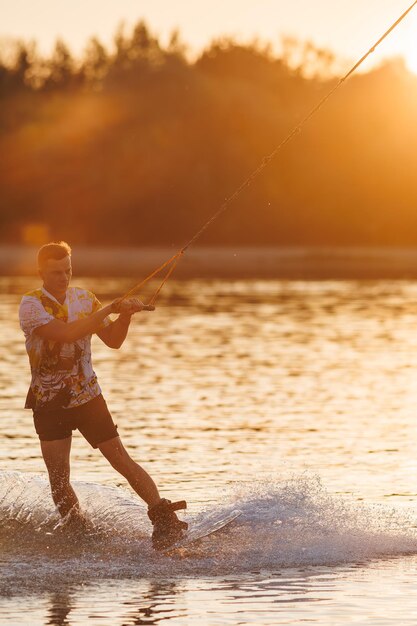 An athlete performs a trick on the water Park at sunset Wakeboard rider