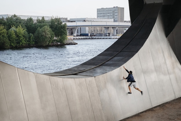 Спортсмен, практикующий фриран, выполняет упражнения для бега по большой стене.