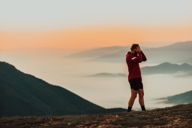 An athlete rests on top of a mountain after exhausting running training.