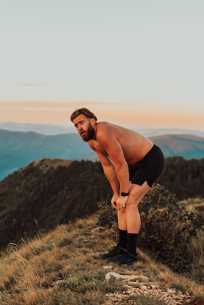 An athlete rests on top of a mountain after exhausting running training.