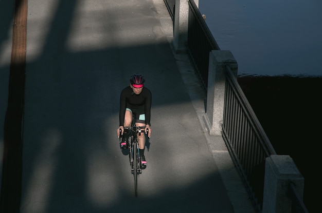 Athlete rides a bike along the embankment at sunrise